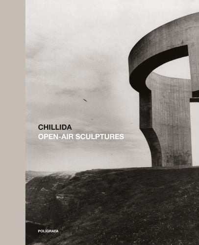 Monumental grey tower sculpture in bleak urban landscape, CHILLIDA OPEN-AIR SCULPTURES in black and white font to centre left.