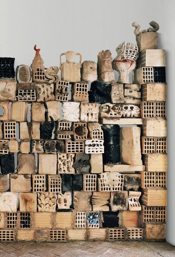 Stack of wood and ceramic objects, blocks with holes in exhibition space.