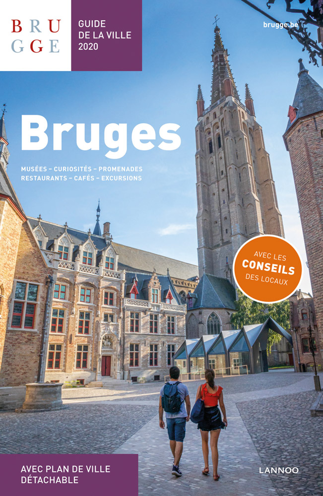 Gothic building, The Church of Our Lady, with 2 tourists in square below, on cover of 'Bruges. Guide de la Ville 2020, by Lannoo Publishers.