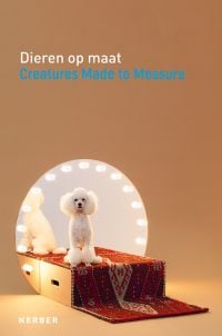 White poodle sitting on red rug covered box, round dressing room mirror with lights behind, beige cover, Dieren op maat Creatures Made to Measure in white and blue font above.