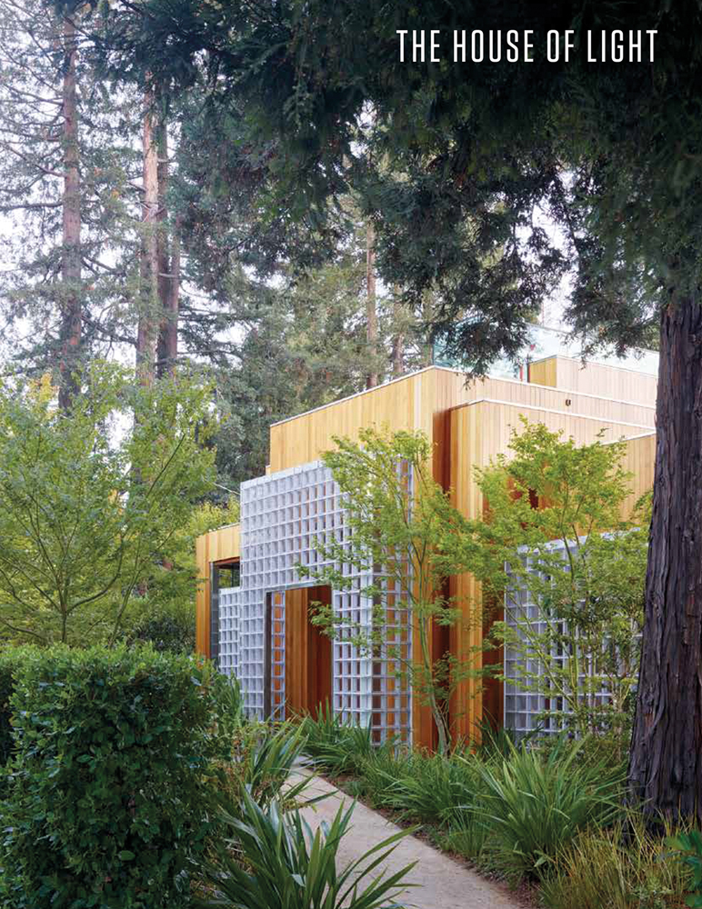 Façade of modern house with wood exterior and pale grey grid panels, surrounded by green trees, THE HOUSE OF LIGHT in white font to top right.