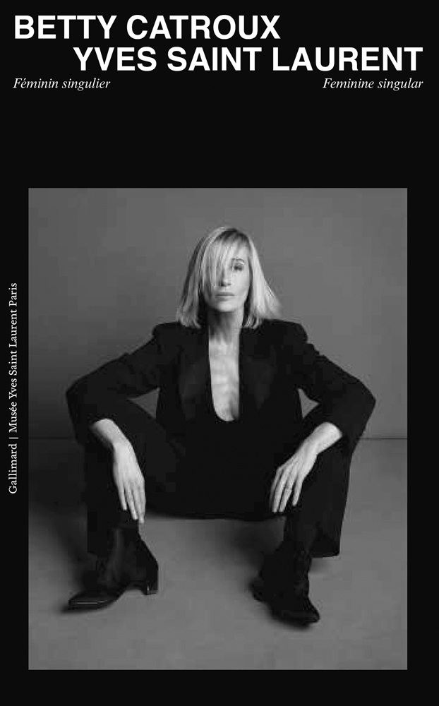 Women in black suit sitting on floor, on black cover of 'Betty Catroux, Yves Saint Laurent, Feminine Singular', by Editions Gallimard.