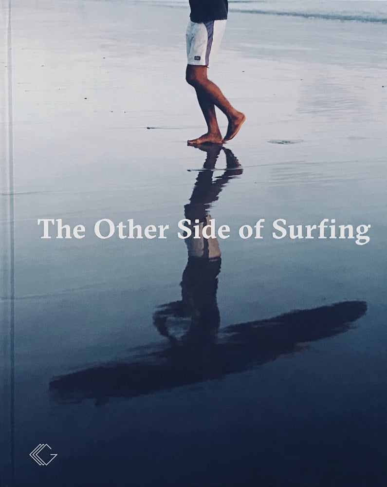 Reflection of male surfer on sand carrying surfboard, The Other Side of Surfing in white font to centre.