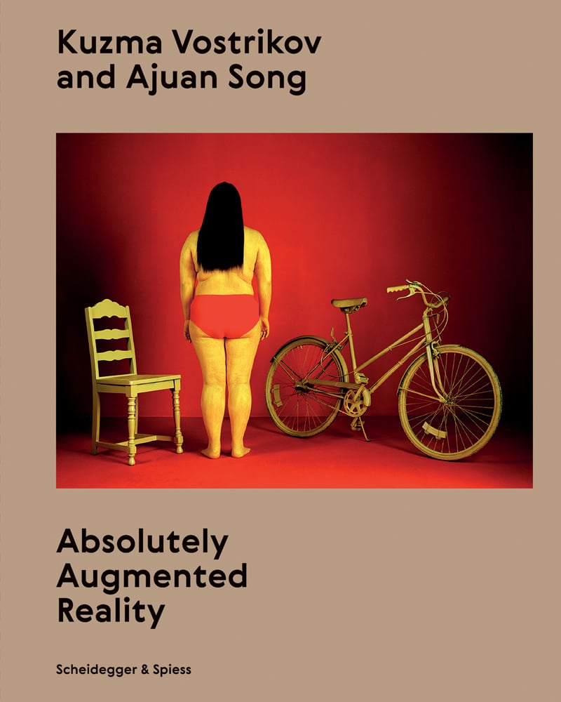 Back of female figure in red knickers, in-between a chair and pushbike, brown cover, Kuzma Vostrikov and Ajuan Song Absolutely Augmented Reality in black font above and below.