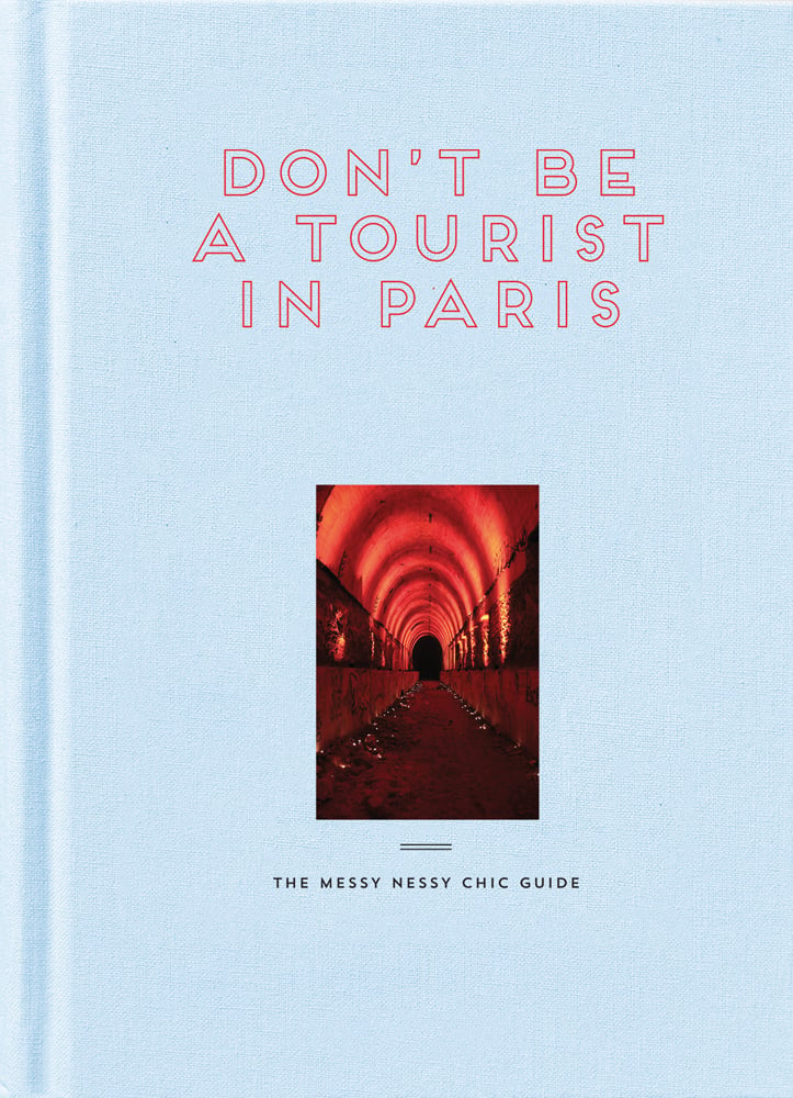 Arched underpass illuminated in red, on pale blue cover, DON'T BE A TOURIST IN PARIS in outlined red font above.
