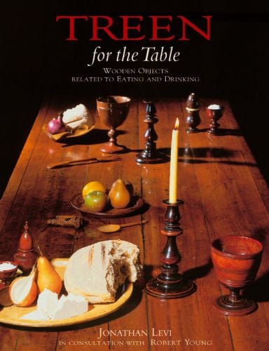 Long wooden table with turned wood objects: goblets, candlestick holder, plate, on cover of 'Treen, For the Table: Wooden Objects Related to Eating and Drinking', by ACC Art Books.