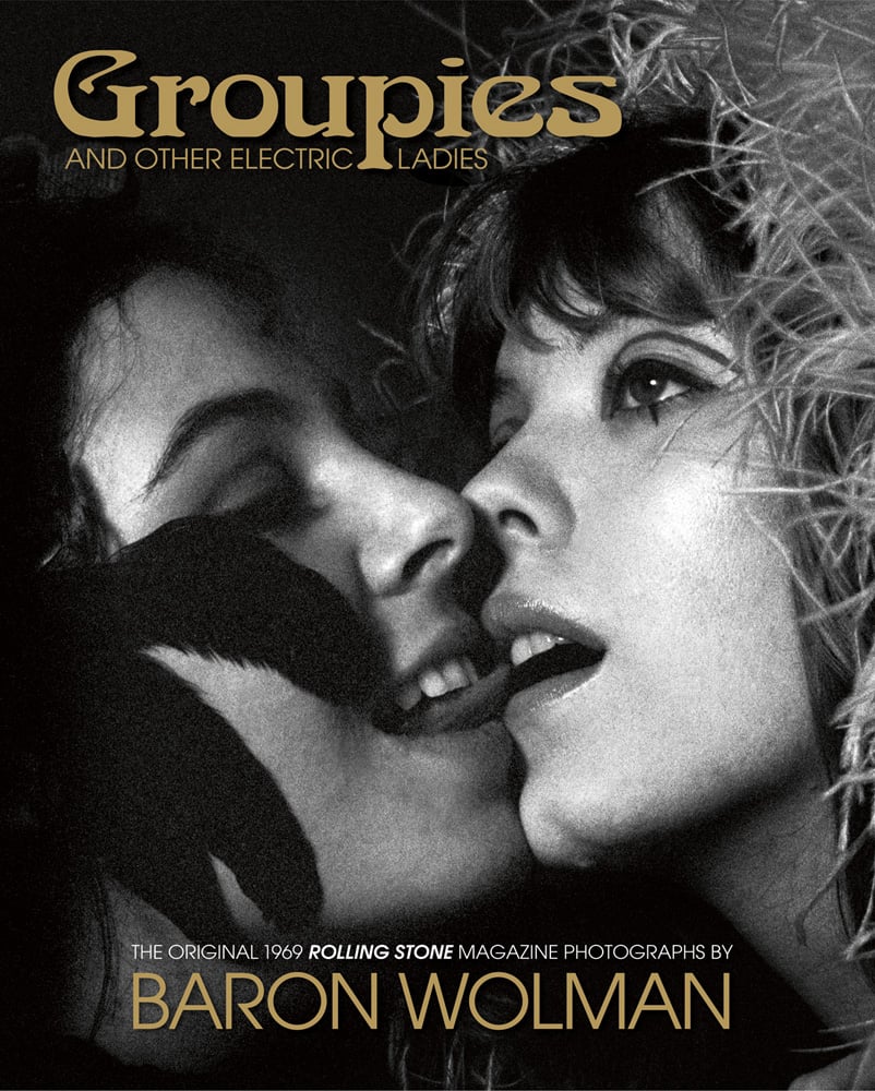 Two white female 'groupies', one with tongue near the others mouth, 'Groupies AND OTHER ELECTRIC LADIES', in gold font above.