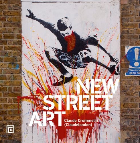 Graffiti artwork on white door, of young white boy jumping in air over red, orange and yellow explosion of paint, on cover of 'New Street Art', by ACC Art Books.