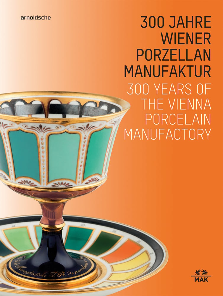 Gold, orange, turquoise porcelain goblet and saucer, on orange cover, 300 Years of the Vienna Porcelain Manufactory in white font