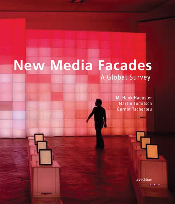 Interior of Media Facade Exhibition with wall of illuminated pink square screens on cover of 'New Media Facades: A Global Survey', by Avedition Gmbh.