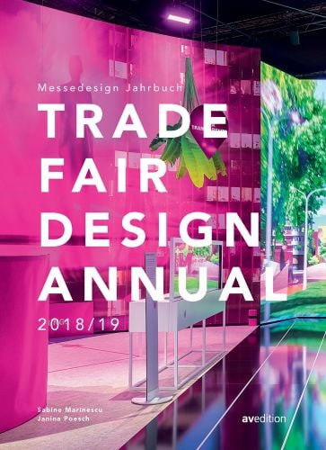 Exhibition interior, figure in pink projected onto suspended wall, Trade Fair Design Annual 2018/19 in white font across centre