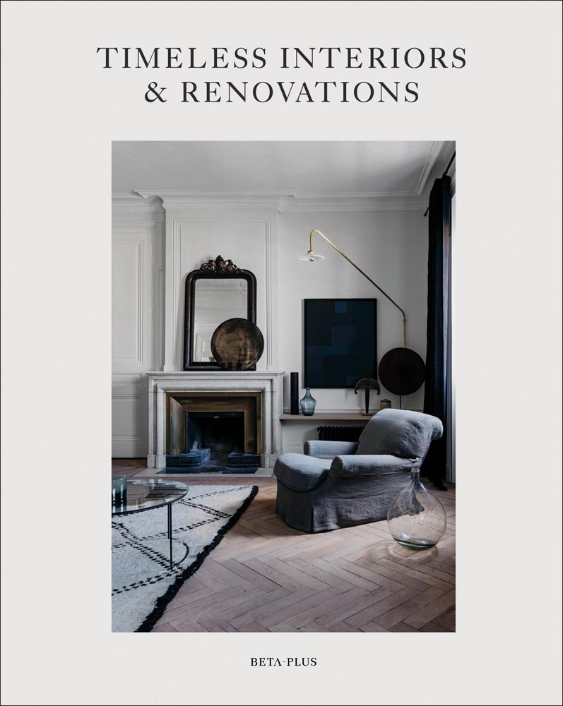 Interior living space, sofa chair, fireplace, herringbone flooring, on cover of 'Timeless Interiors & Renovations', by Beta-Plus.