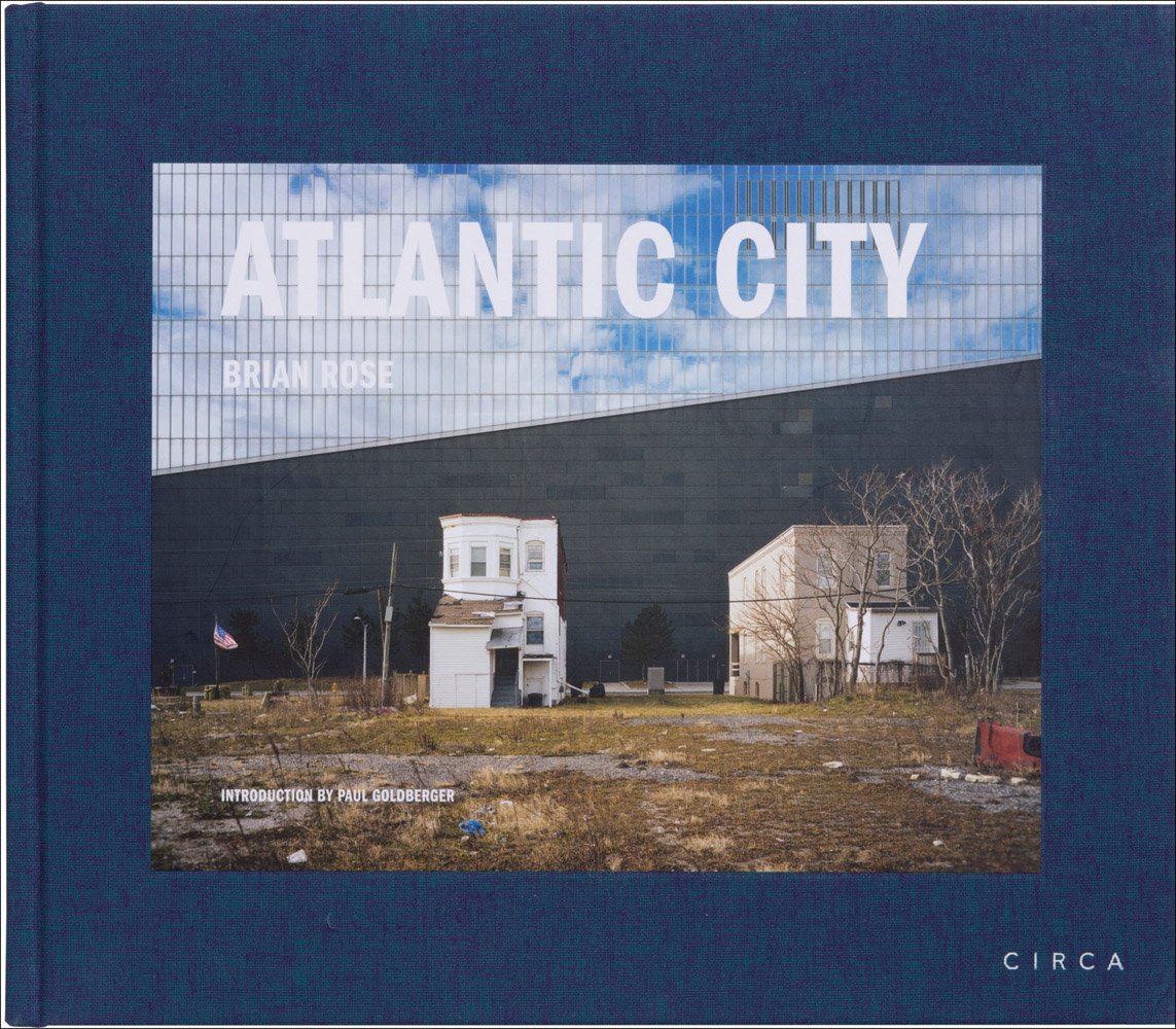 Two derelict flat roofed buildings in desolate landscape, on blue cover of 'Atlantic City', by Circa Press.
