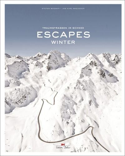 Aerial view of snow covered mountains with winding road, on cover of 'Escapes: Winter', by Delius Klasing.