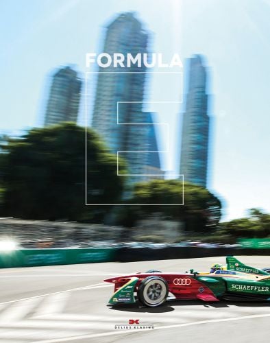 Green and red AUDI Formula E racing car turning on track, skyscrapers behind, Formula in white font, large E with white outline, to centre