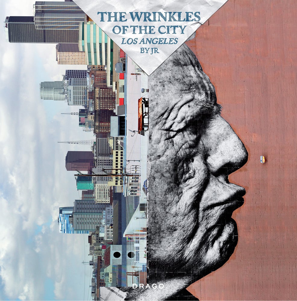 Cityscape rotated left, with wrinkled face to right, on cover of 'The Wrinkles Of The City - Los Angeles', by Drago.