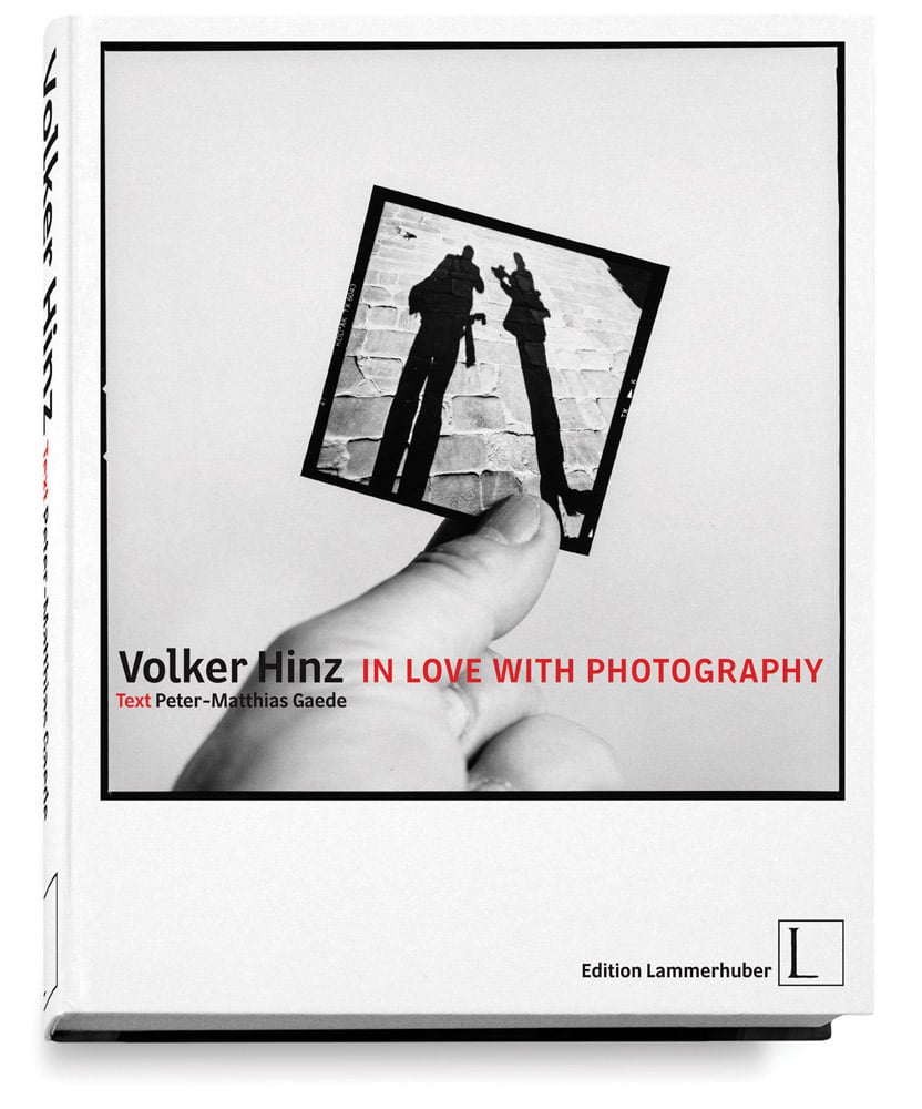 Left hand holding a polaroid photo of two silhouettes of people, on white cover of 'In Love with Photography', by Edition Lammerhuber.
