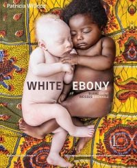 Two naked babies sleeping side by side: one albino baby, one black baby, on colorful sheet, on cover of 'White Ebony', by Edition Lammerhuber.