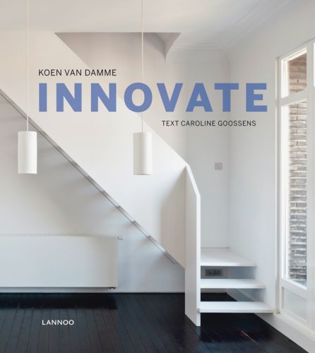 Residential interior with white wooden staircase, black wood flooring, two low hanging lights, on cover of 'Innovate', by Lannoo Publishers.