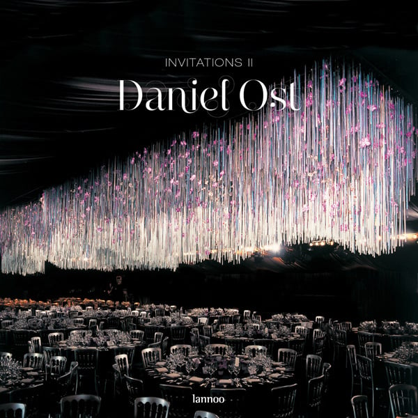 Spectacular display of glass tubes with pink flowers hanging from ceiling of function room with round tables, on cover of 'Invitations Il, Daniel Ost', by Lannoo Publishers.