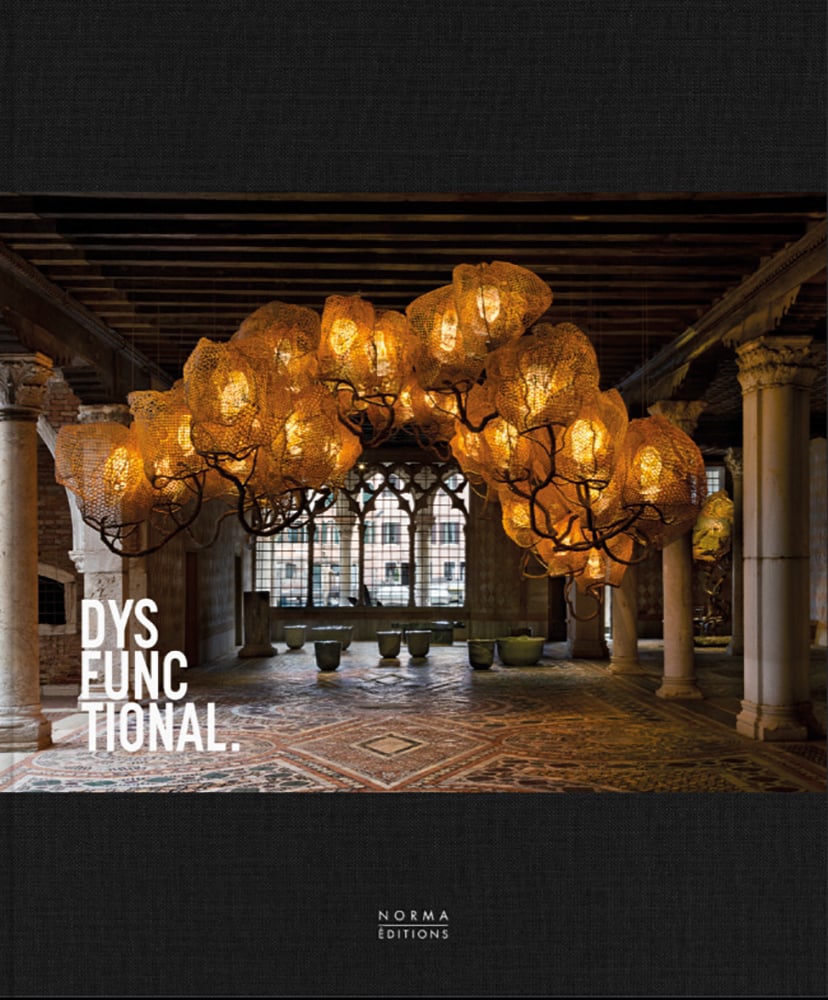 Large illuminated lighting sculpture with bulbous shapes hanging in grand hall with pillars, on cover of 'Dysfunctional, Beyond the Boundaries of Form and Function', by Editions Norma.
