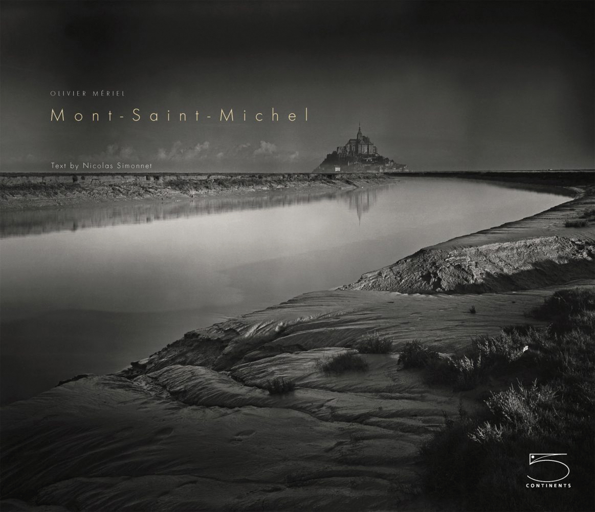 Landscape book cover of Mont-Saint-Michel, Immensity, featuring an atmospheric black and white shot of the monument under black sky. Published by 5 Continents Editions.
