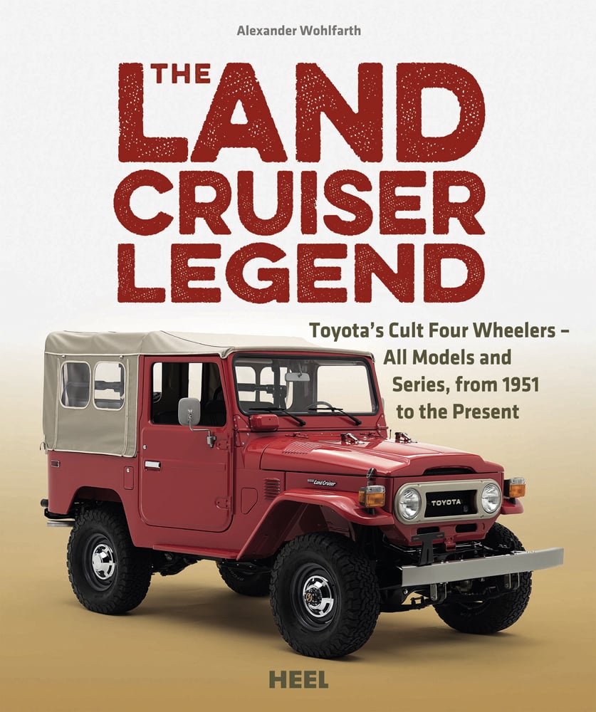 Red Toyota Land Cruiser soft-top, sandy cover, THE LAND CRUISER LEGEND in red font above