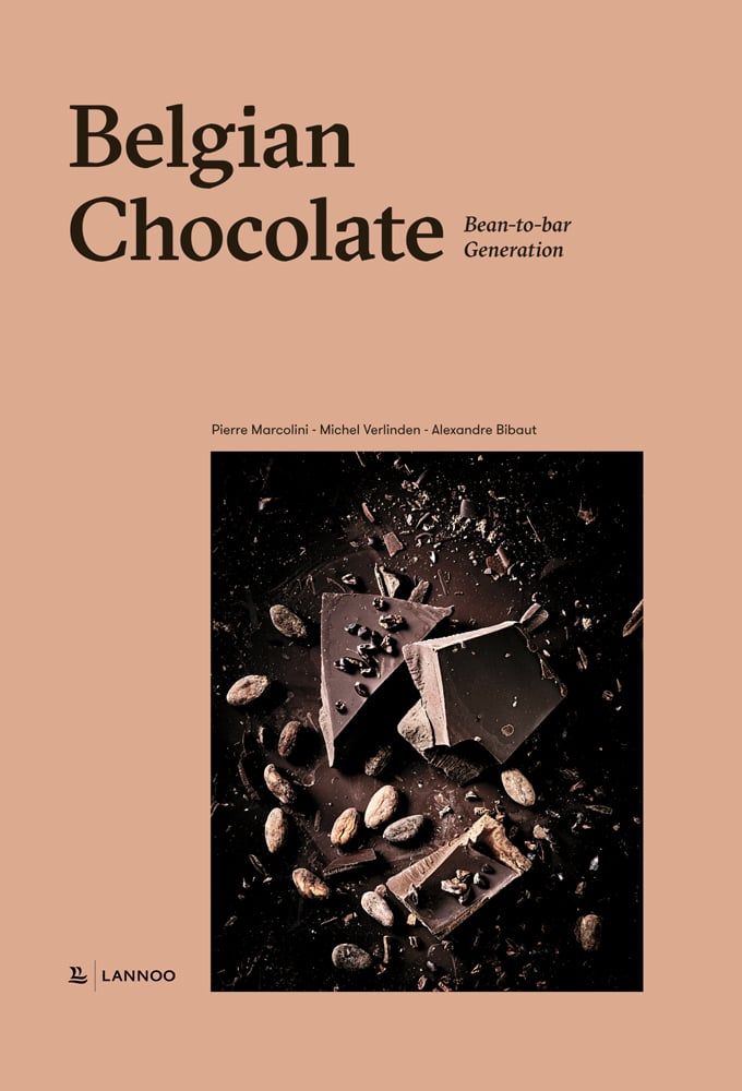 Broken chocolate pieces with cocoa beans, on beige cover of 'Belgian Chocolate Bean-to-Bar Generation', by Lannoo Publishers.