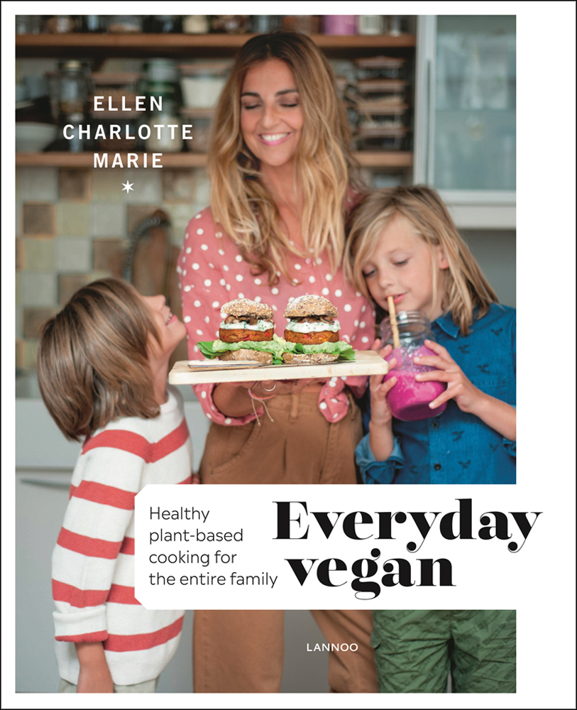 Ellen Charlotte Marie holding plate of vegan burgers, her two children standing either side, on white cover, 'Everyday Vegan, Healthy Plant-Based Cooking for the Entire Family', by Lannoo Publishers.