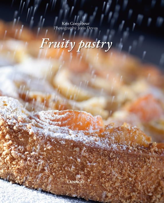 Fruit pie being dusted with icing sugar, on cover of 'Fruity Pastry', by Lannoo Publishers.