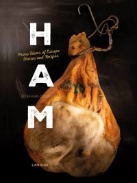 Ham hock with metal hook, tied with string, on charcoal cover of 'Ham, Prime Hams of Europe Stories and Recipes', by Lannoo Publishers.