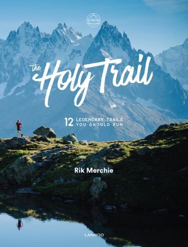 Snow mountain landscape with lone runner below, The Holy Trail in white font to centre