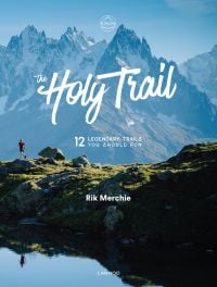 Snow covered mountain landscape with lone runner below, on cover of 'The Holy Trail, 12 Legendary Trails You Should Run', by Lannoo Publishers.