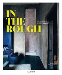Dark industrial interior living space, with navy fireplace, on cover of 'In the Rough, Raw Interiors and Rugged Makers', by Lannoo Publishers.