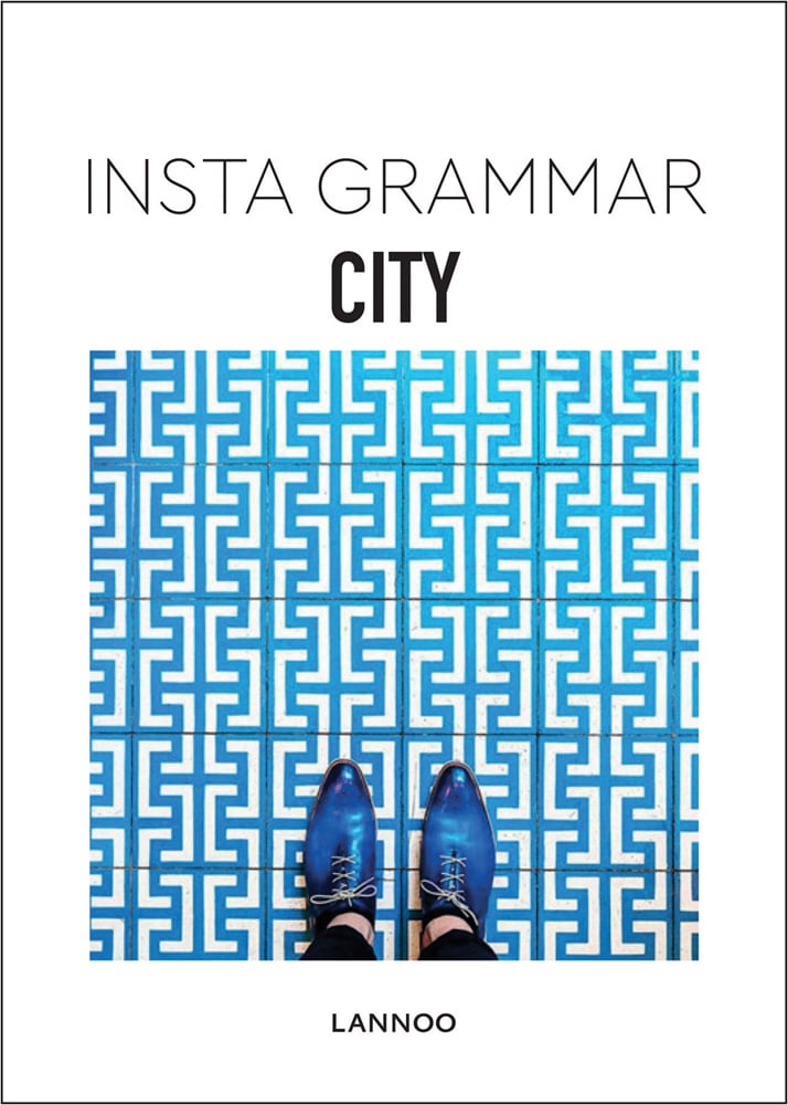 Aerial shot of pointed blue shoes on blue and white tiled floor, on white cover of 'Insta Grammar: City', by Lannoo Publishers.