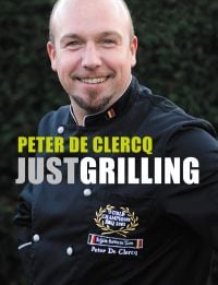 World barbecue Champion Peter de Clercq in black chef top, smiling at camera, on cover of 'Just Grilling', by Lannoo Publishers.
