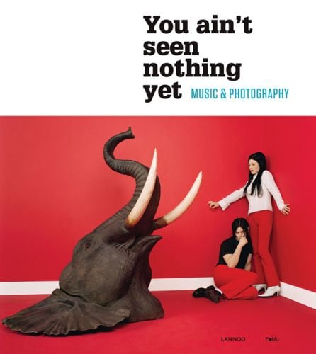 Members of the White Stripes band in corner of room staring at elephant head, on cover of 'You Ain't Seen Nothing Yet: Music and Photography', by Lannoo Publishers.