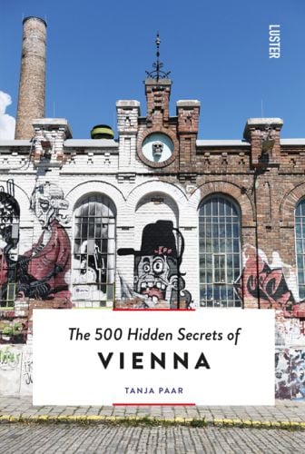 Graffitied brick building, skull inset to top, The 500 Hidden Secrets of Vienna in black font on white banner below