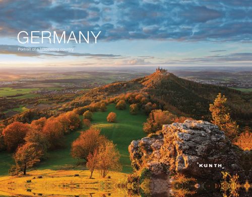 Vast aerial landscape photograph, green hills with trees, blue sky, Germany in white font to upper left