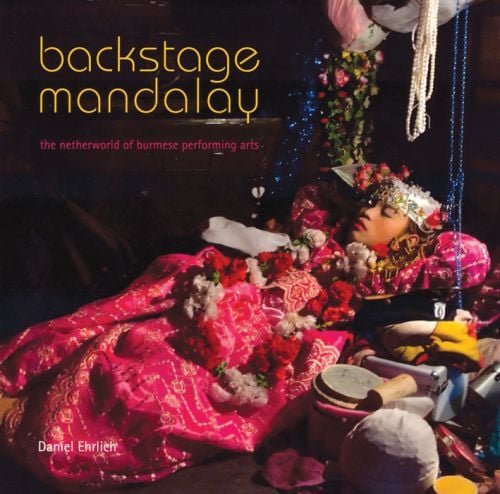 Performing arts theatre scene with young Burmese girl wrapped in pink cloth, flowers on top, on cover of 'Backstage Mandalay', by River Books.