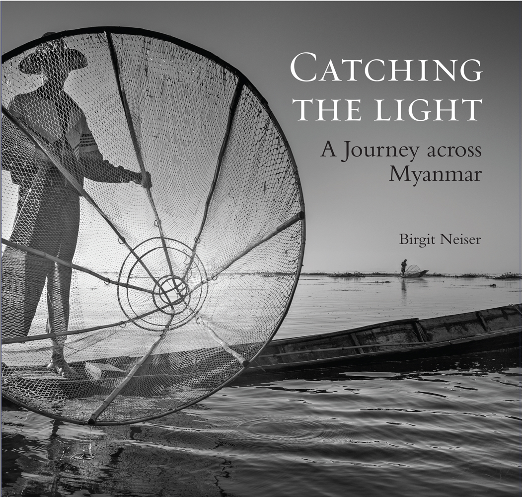 Intha fisherman standing on end of boat in Inle Lake, Myanmar, to cover of 'Catching the Light', by River Books.