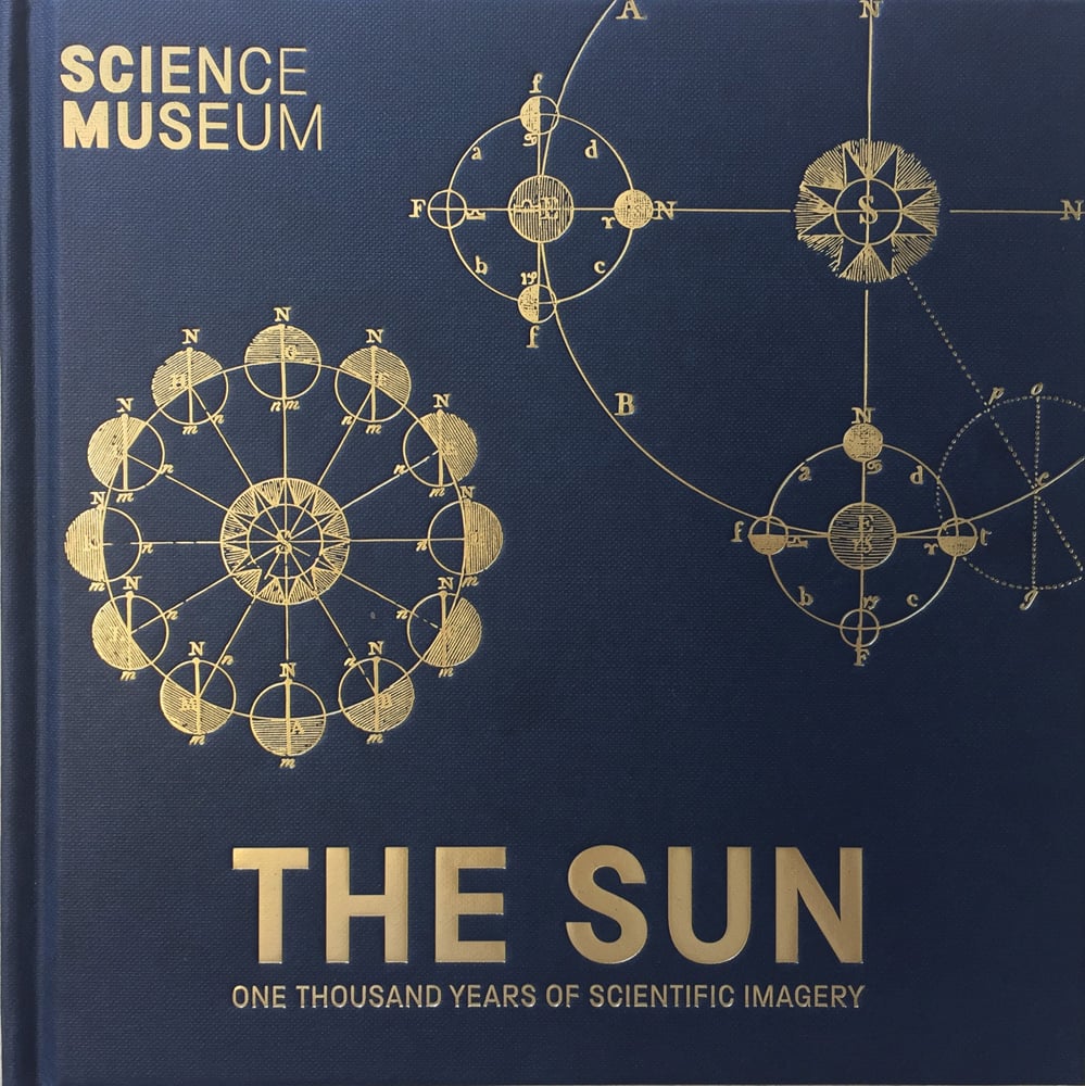 Gold embossed diagram of compass and Earth's orbit around sun, on navy cover, THE SUN One Thousand Years of Scientific Imagery in gold font below