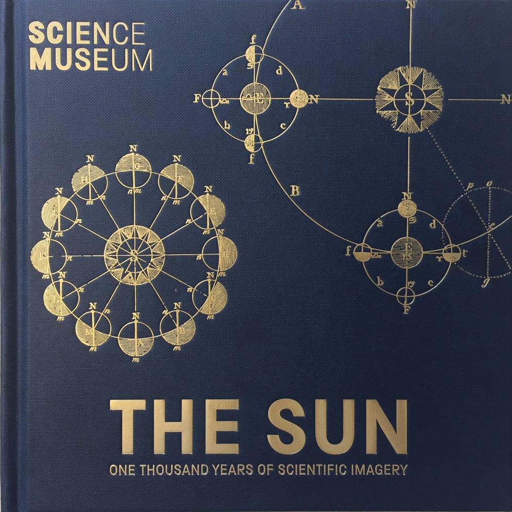 Gold embossed diagram of compass and Earth's orbit around sun, on navy cover, THE SUN One Thousand Years of Scientific Imagery in gold font below