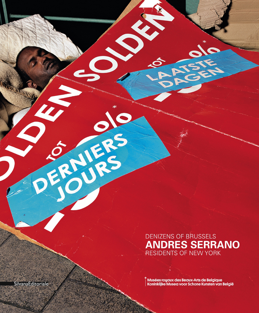 Sleeping black homeless man laying under red cardboard, ANDRES SERRANO in white font to lower right