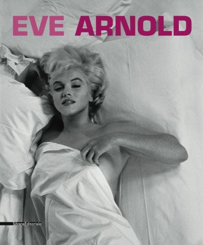 Marilyn Monroe wrapped in white bed sheet, naked, left hand to chest, EVE ARNOLD in pink font above