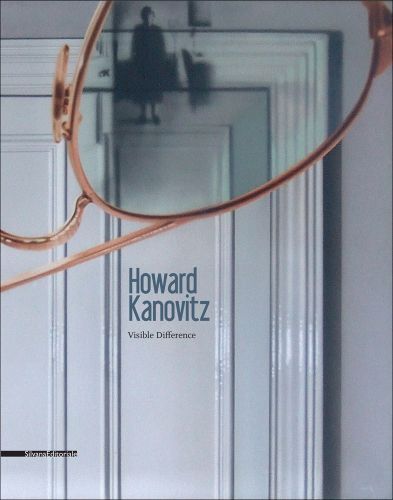 White interior door, rose gold rimmed glasses upside down in front, figure in lens, Howard Kanovitz in blue font near centre