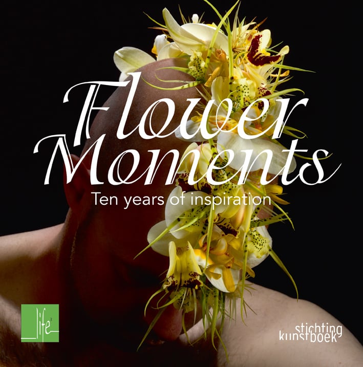 Book cover of Flower Moments, Ten Years of Inspiration, with the bald head of a man with white and yellow flower arrangement on top. Published by Stichting.