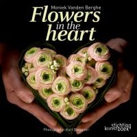 Book cover of Flowers in the Heart, with a pair of hands holding a heart-shaped flower arrangement of pale pink roses. Published by Stichting.