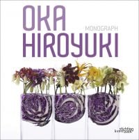 White book cover of Hiroyuki Oka, Monograph, with three glass vessels containing a half of a red cabbage with various colored orchids on top. Published by Stichting.