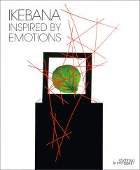White book cover of Ikebana Inspired by Emotions, featuring a box with a green leaf inside, with an abstract sculpture of red sticks. Published by Stichting.